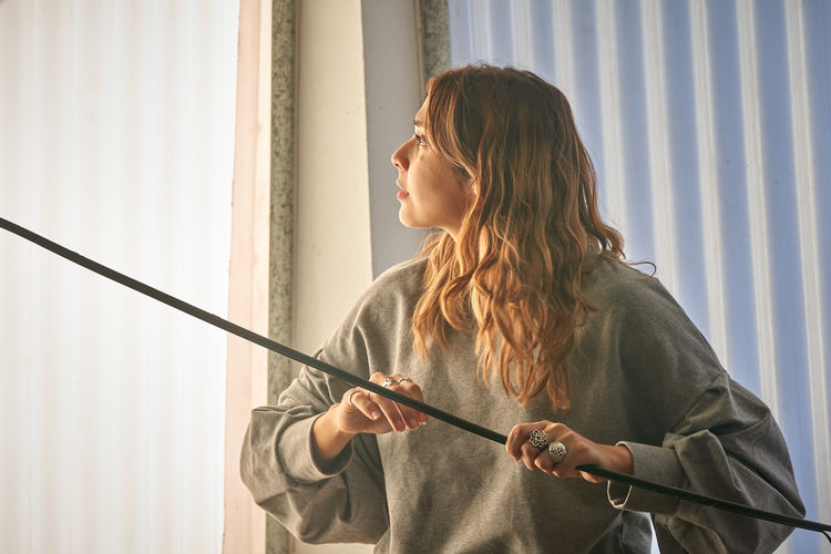 Side view of young woman looking through window