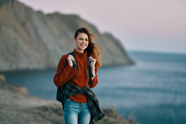 Portrait of smiling young woman standing in sea