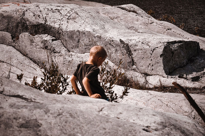 Boy sitting on rock by  lake