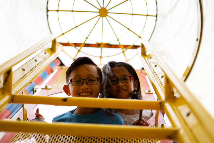 Portrait of siblings standing at play equipment