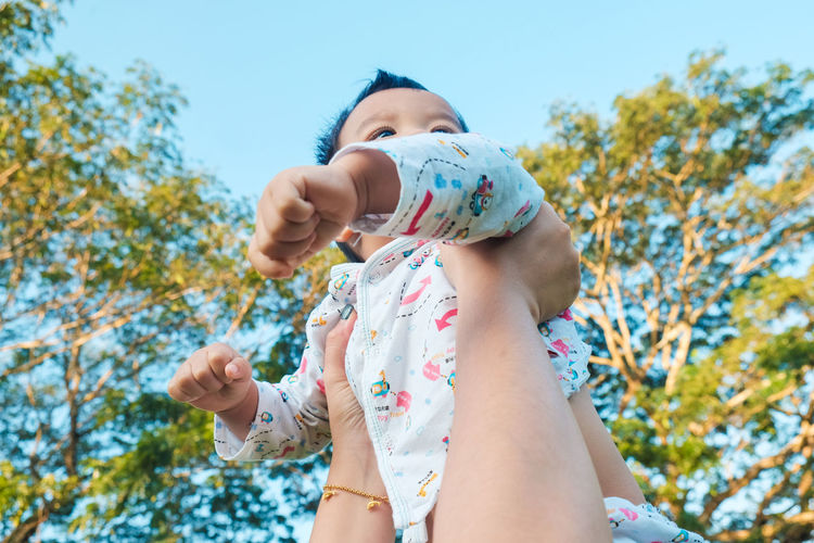 Cropped hand holding cute baby boy outdoors