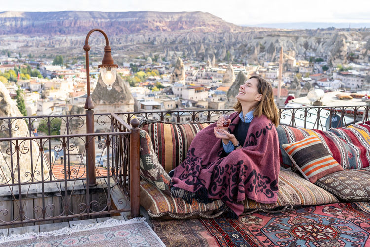 Happy woman is drinking tea on a balcony in cappadocia, turkey