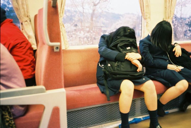 Students with backpacks sleeping while traveling in train