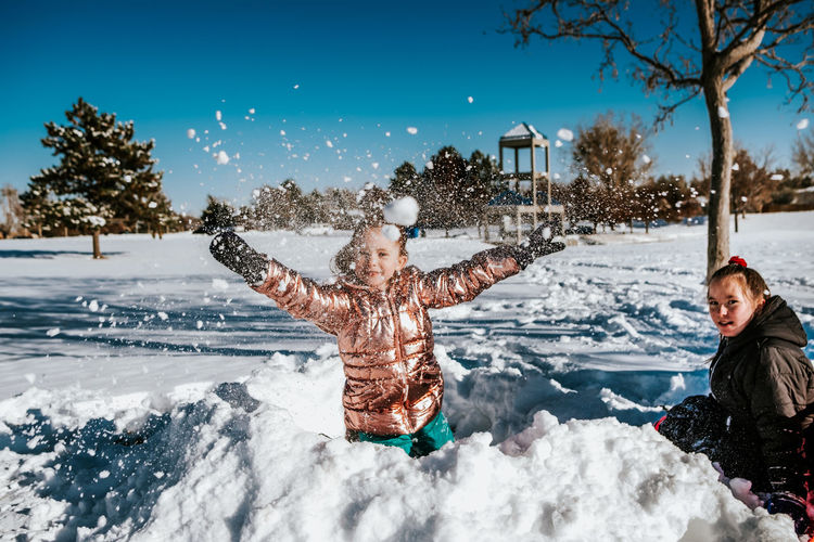 Action shot of young girl throwing a snowball during winter