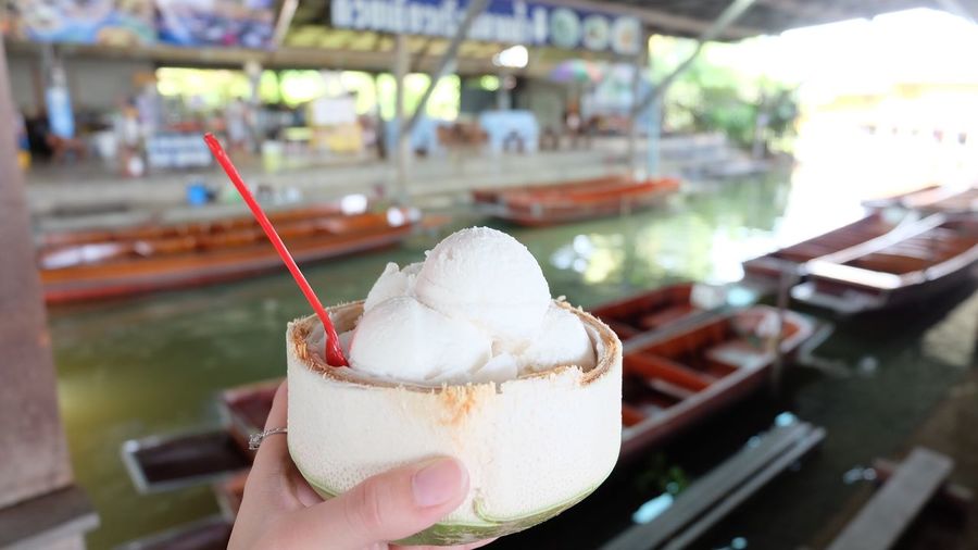Cropped hand of person holding ice cream in coconut