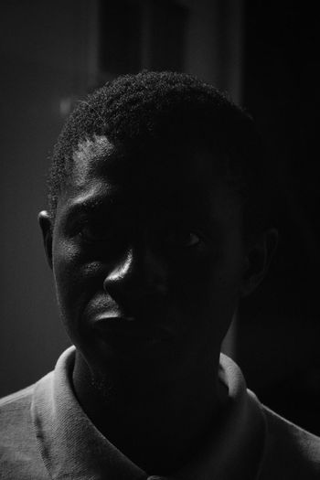 Close-up portrait of young man against black background