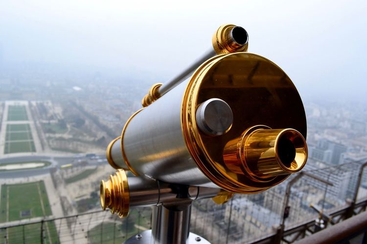 Gilded coin-operated binoculars at observation point with landscape in background