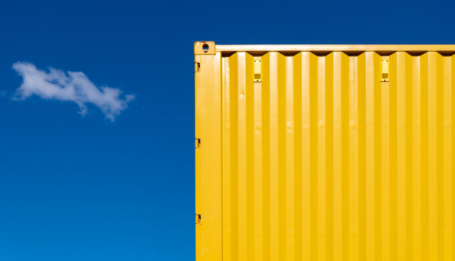 Low angle view of yellow cargo container against sky