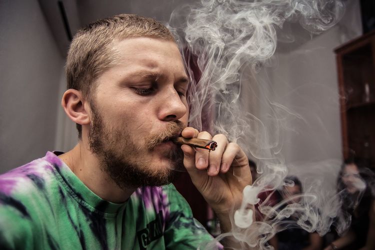 Close-up of young man smoking marijuana joint