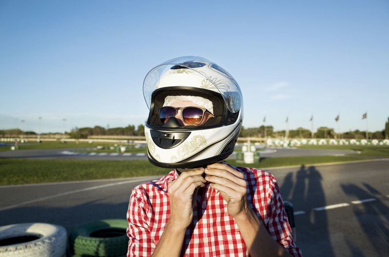 Close-up of man wearing helmet while standing at motor racing track