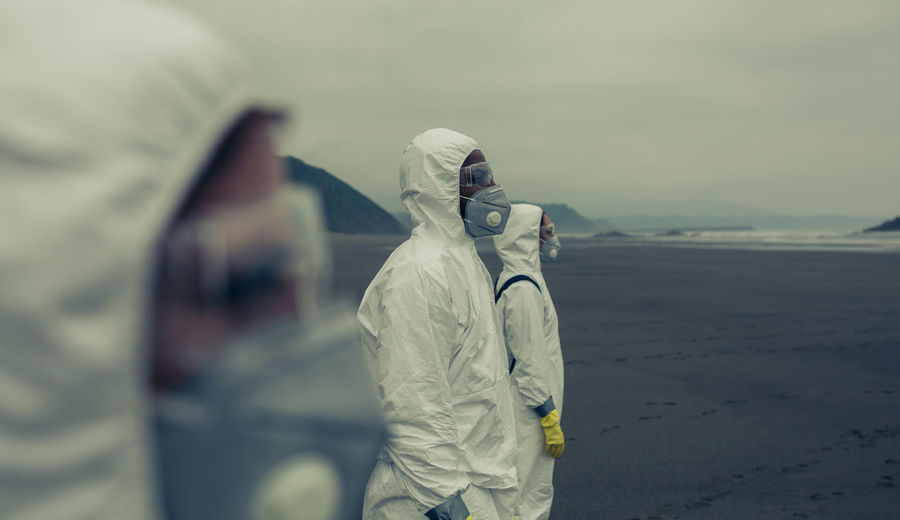 Doctors in protective workwear standing at beach