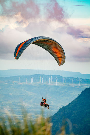 Person paragliding flying against sky
