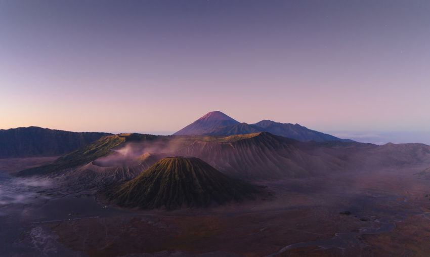 Scenic view of volcanoes against clear sky during sunset