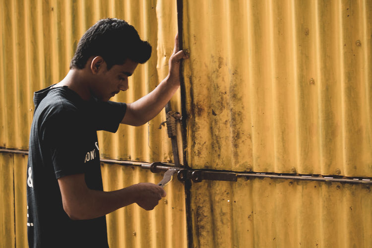 Boy standing against rusty door
