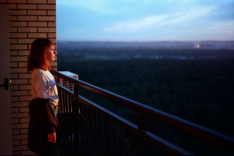 Woman looking at view while standing by railing in balcony