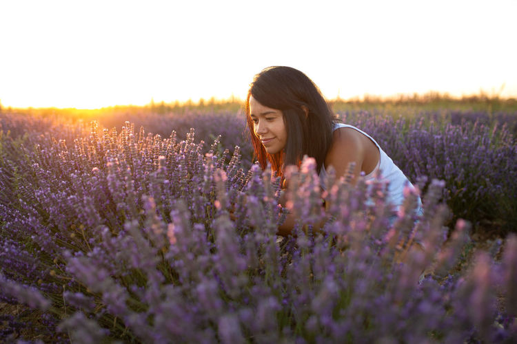 Young latin woman enjoys nature amidst lavender flowers at sunset