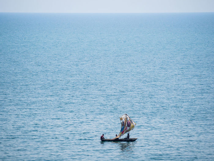 People in simple sailing boat on lake tanganyika against sky, zambia