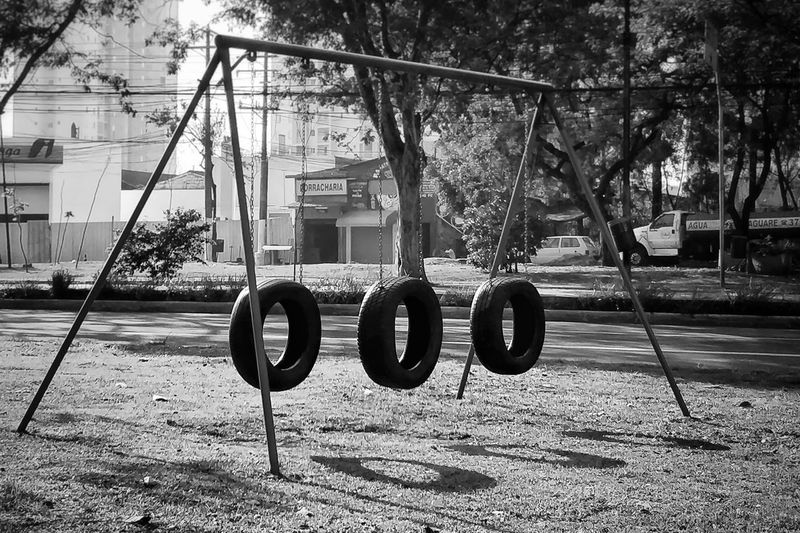 Close-up of swing hanging in park against building