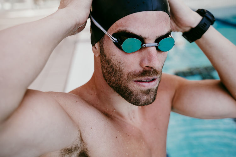 Handsome male swimmer adjusting swimming goggles