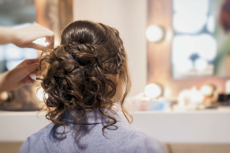 Hairdresser adjusting woman hair at home