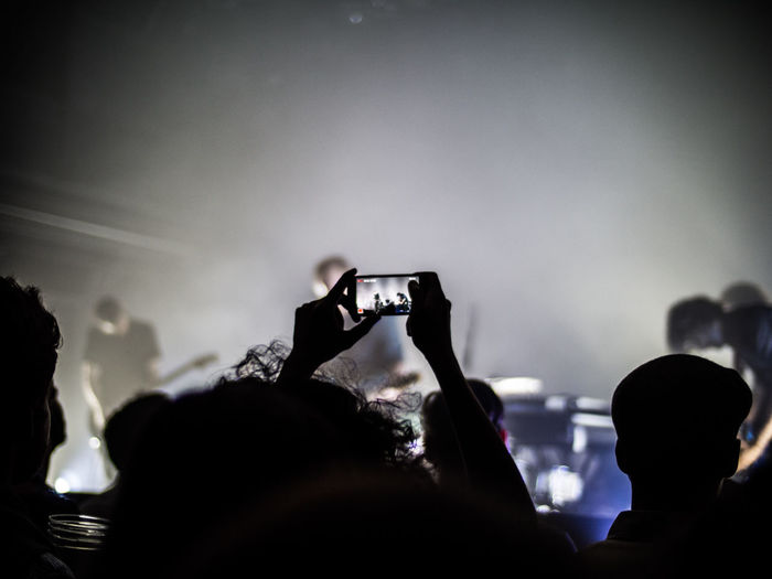 Cropped image of child photographing through smart phone at concert
