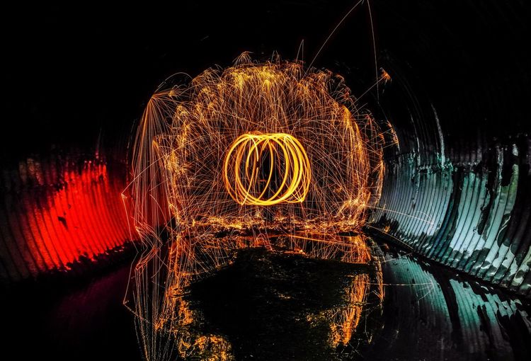 Illuminated wire wool by lake at night