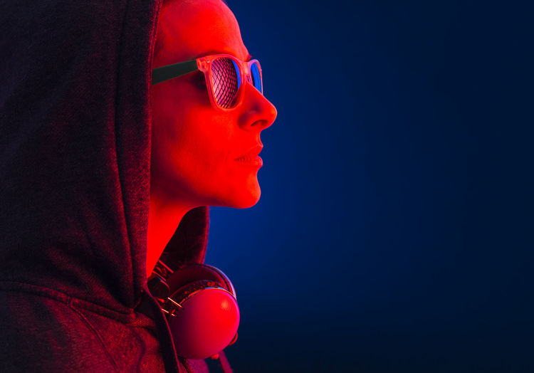 Woman wearing sunglasses in illuminated room