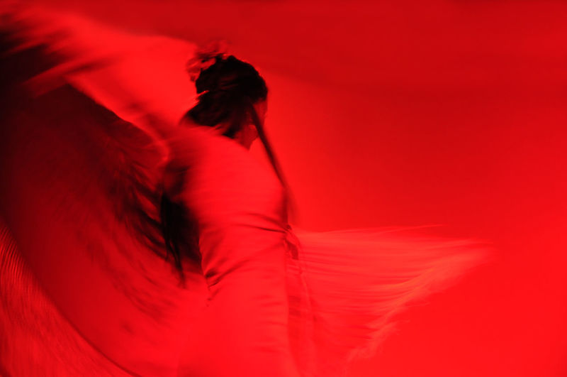 Low angle view of woman dancing against red background