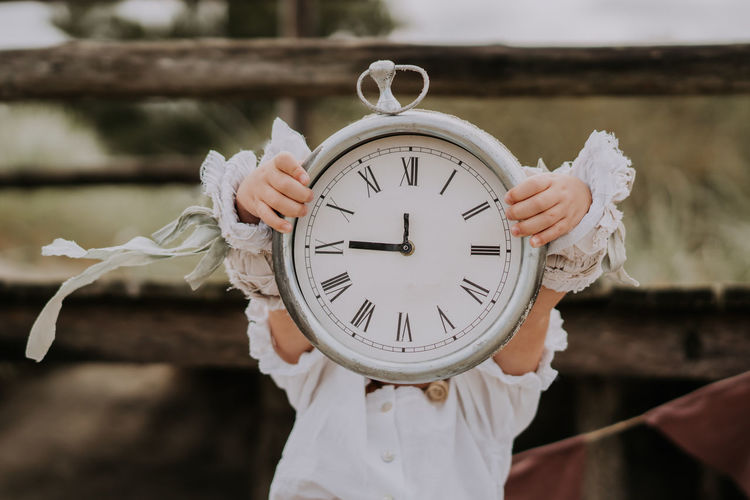 Child girl holding clock in her hands