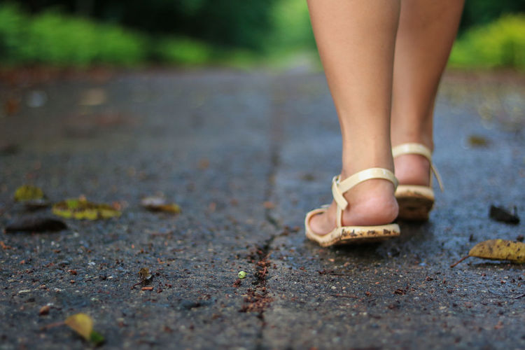 Low section of woman wearing scandals walking on road