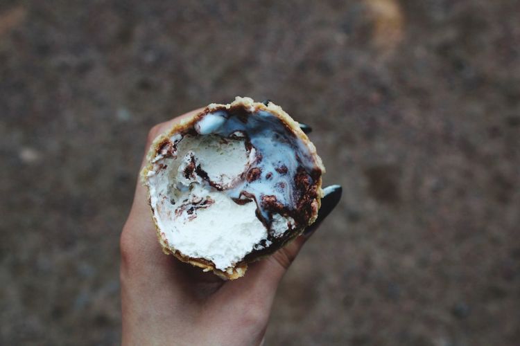 Cropped hand of woman holding eaten ice cream cone on street