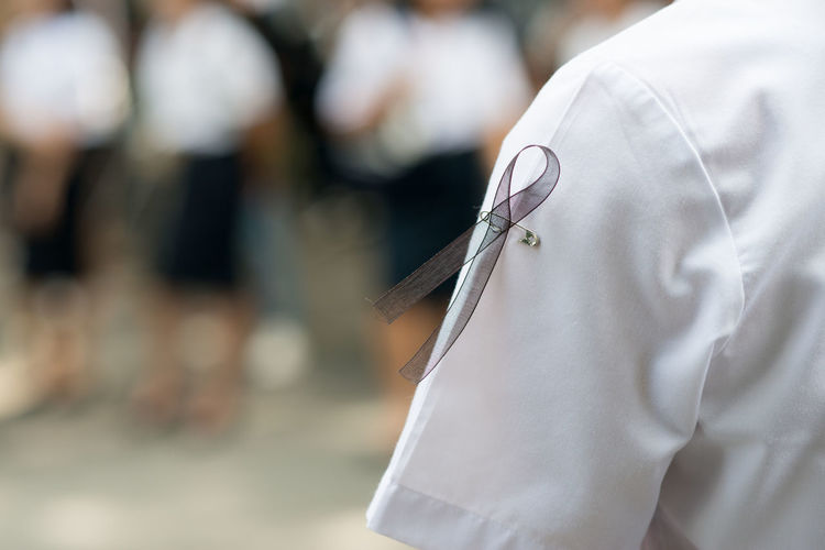 Close-up of safety pin and ribbon on student white uniform