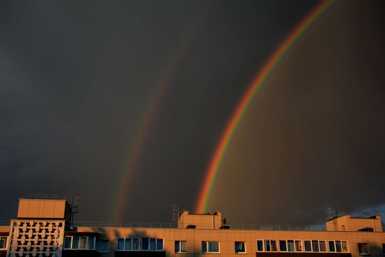 Low angle view of rainbow over buildings in city