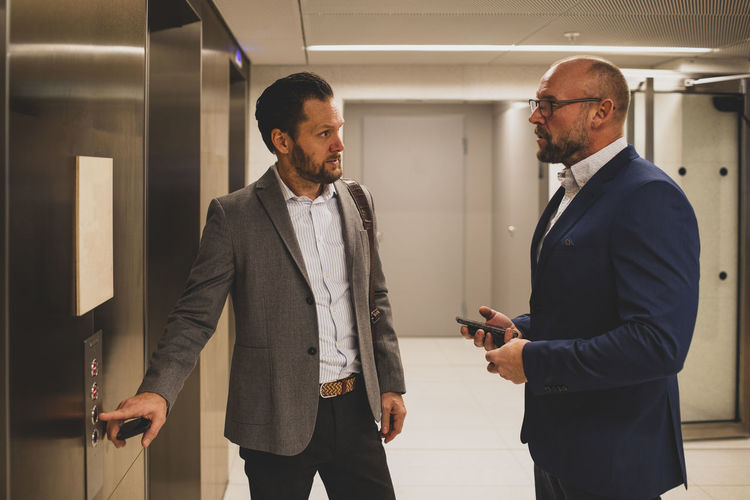 Businessmen talking near office elevator