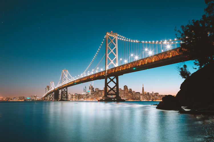 Low angle view of suspension bridge over river at night
