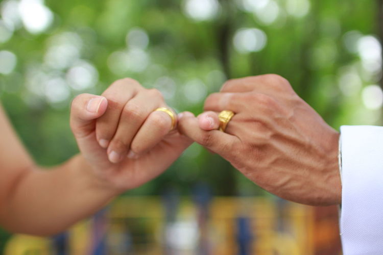 Cropped image of couple taking pinky promise in park