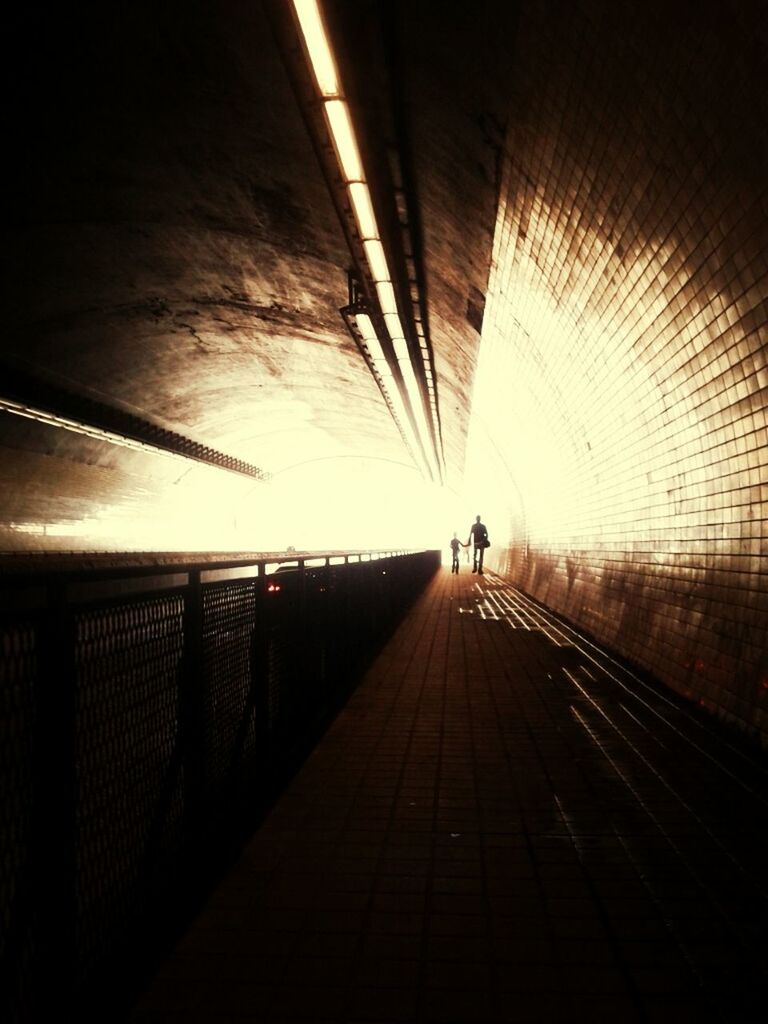 indoors, the way forward, transportation, tunnel, walking, diminishing perspective, ceiling, lifestyles, silhouette, men, built structure, architecture, vanishing point, illuminated, full length, subway, rear view, unrecognizable person