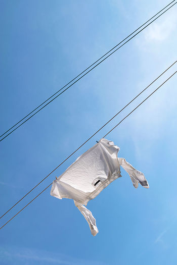 White shirt drying on clothesline at blue sky background. laundry concept.