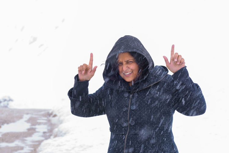 Portrait of smiling woman gesturing while standing in snow
