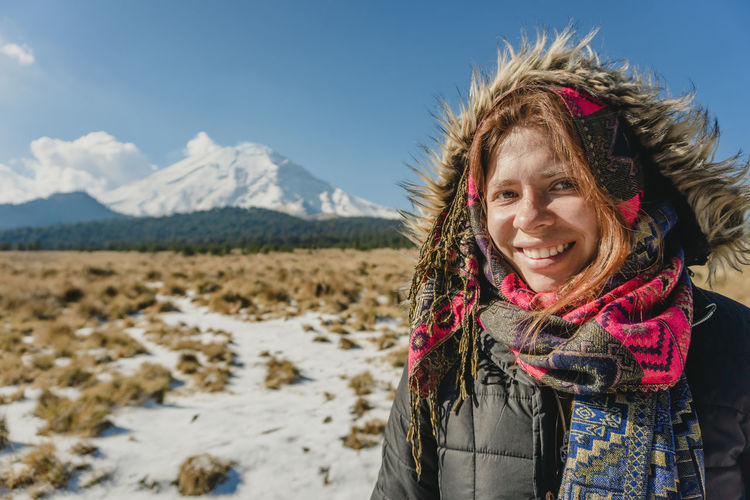 Portrait of young woman standing on snow covered mountain