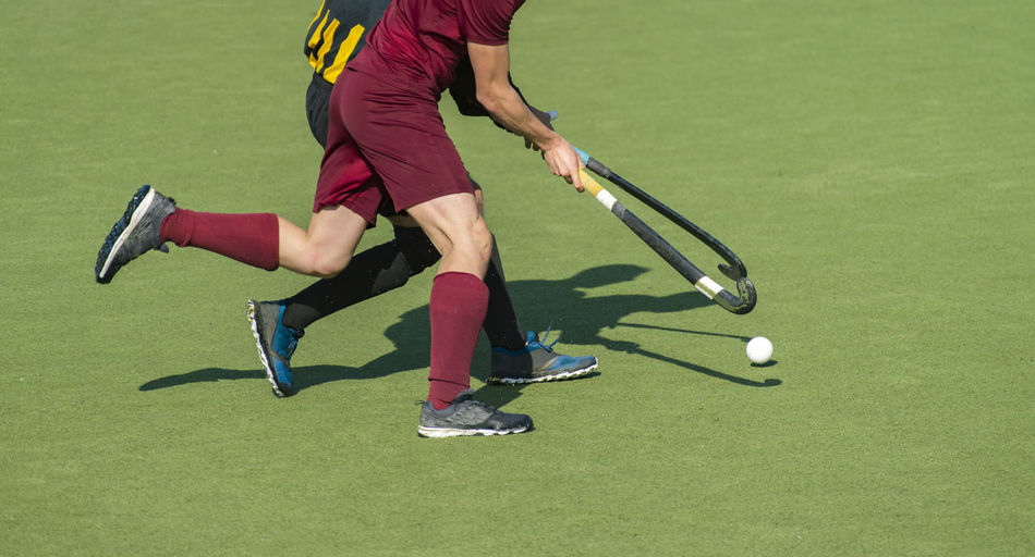 Low section of men playing field hockey