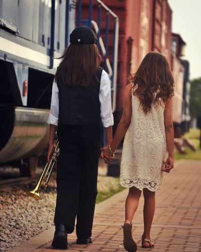 Rear view of boy and girl walking holding hands