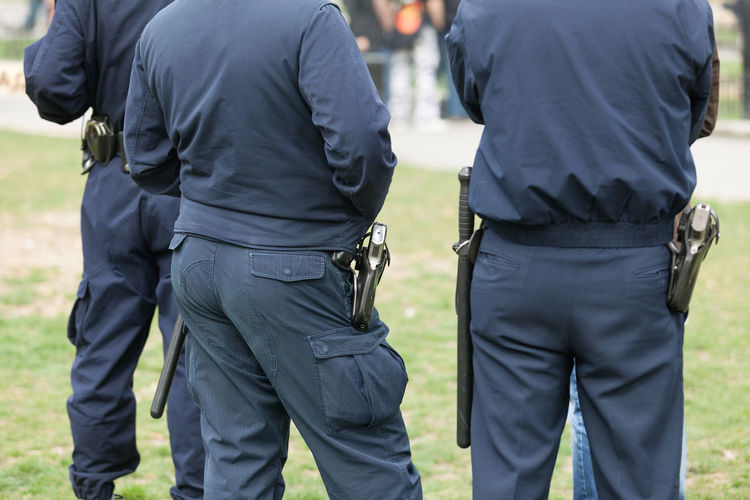 Rear view of police officers standing on grass