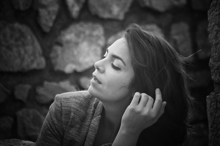 Close-up of woman sitting by stone wall