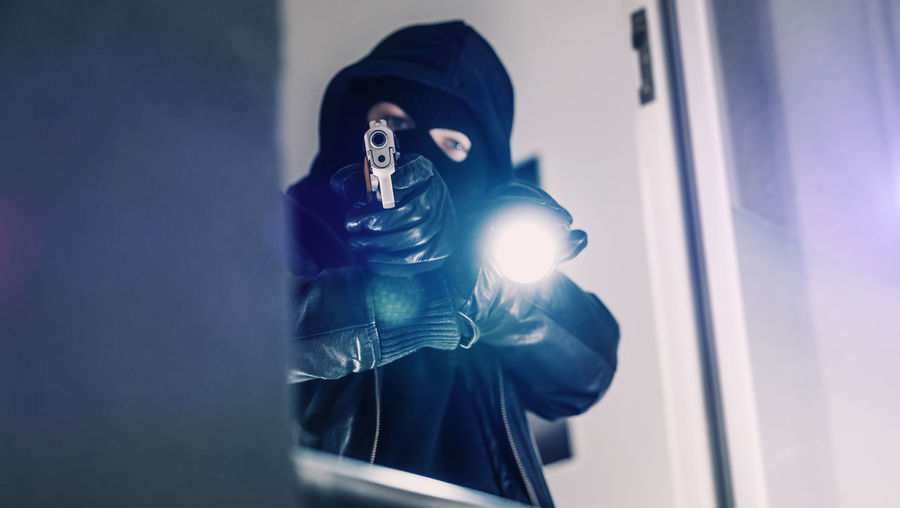 Portrait of thief holding gun at window