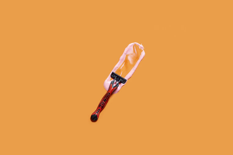 Shaving foam gel and razor on orange background. a multiple use shaving razor and cream. view from