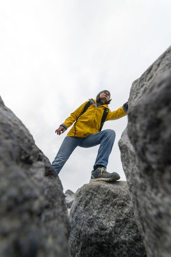 Woman hiker climbing over rocks
