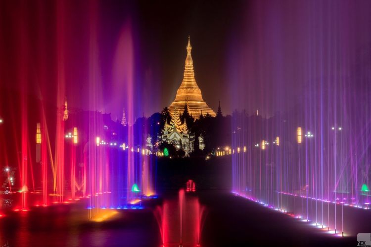 Colorful fountain against illuminated shwedagon pagoda