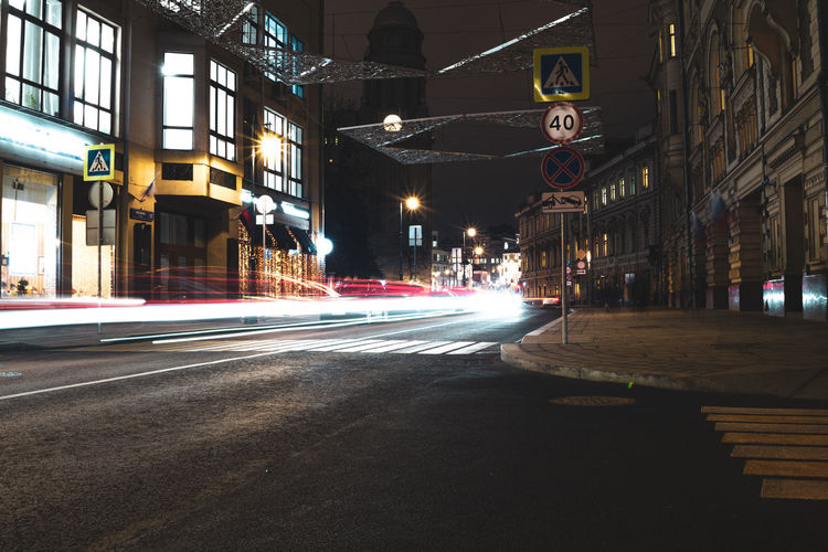 Light trails on street amidst buildings in city at night