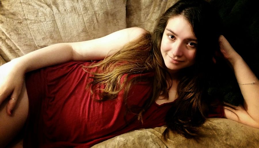 Portrait of beautiful woman smiling while lying on sofa at home